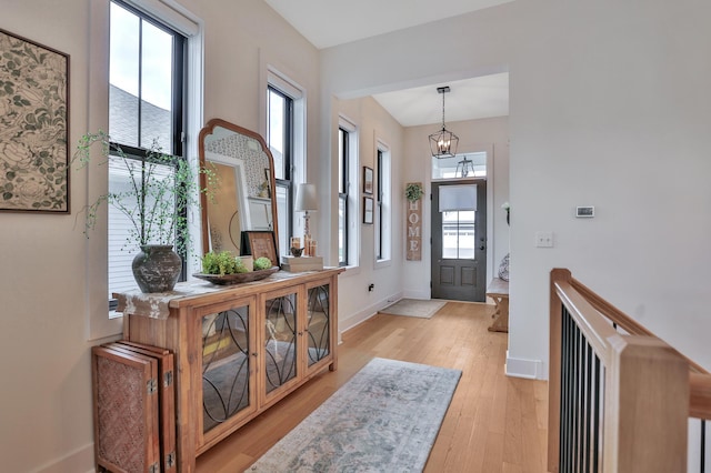 entrance foyer featuring light wood finished floors, baseboards, and a chandelier