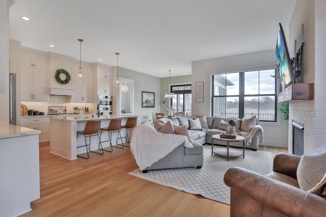 living room with light wood-type flooring, a fireplace, and recessed lighting