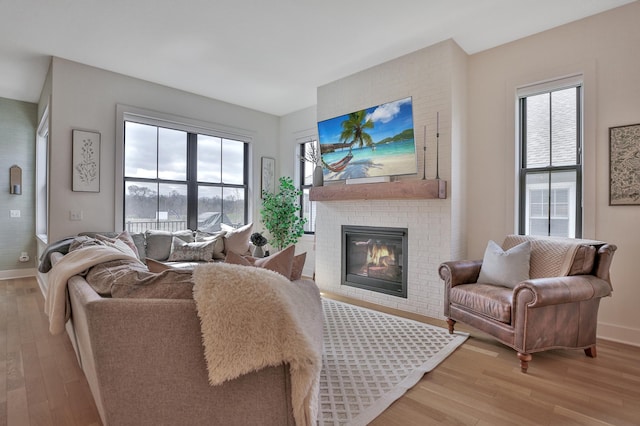 living room featuring a brick fireplace, plenty of natural light, and light wood finished floors