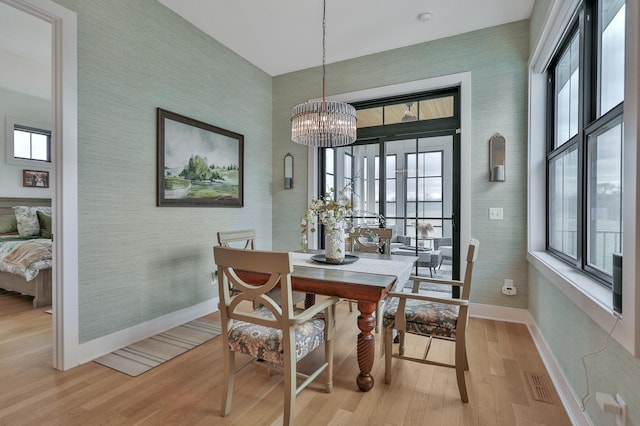 dining area with an inviting chandelier, light wood finished floors, baseboards, and wallpapered walls