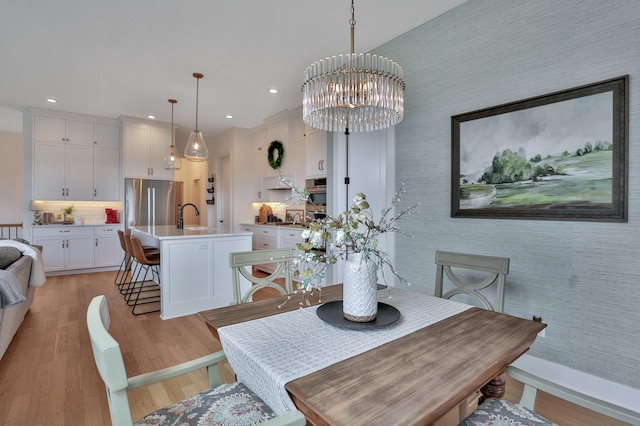 dining space with a chandelier, wallpapered walls, recessed lighting, and light wood-style floors