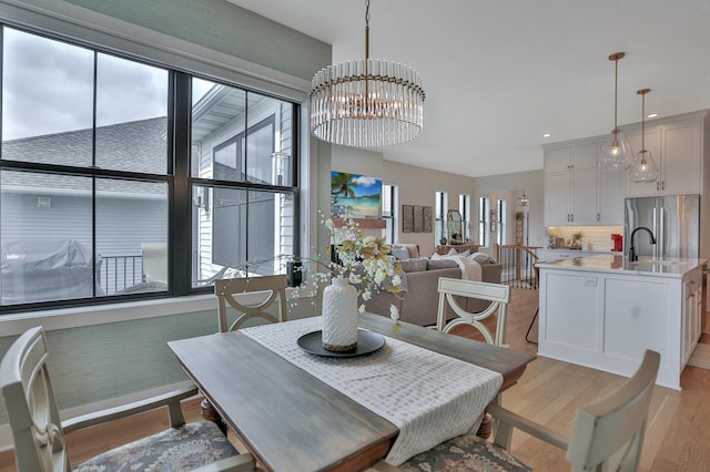 dining room featuring light wood-type flooring, a wealth of natural light, a notable chandelier, and recessed lighting