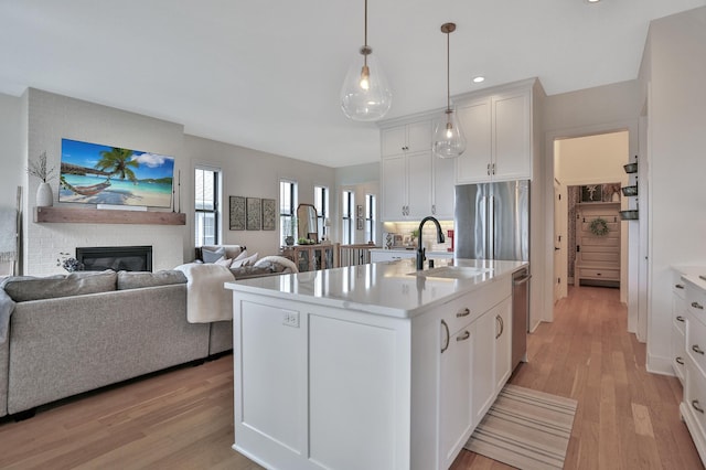 kitchen with a sink, light countertops, stainless steel refrigerator, and light wood-style flooring