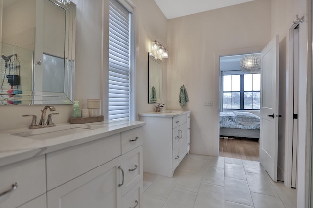 full bath featuring a stall shower, tile patterned flooring, two vanities, and a sink