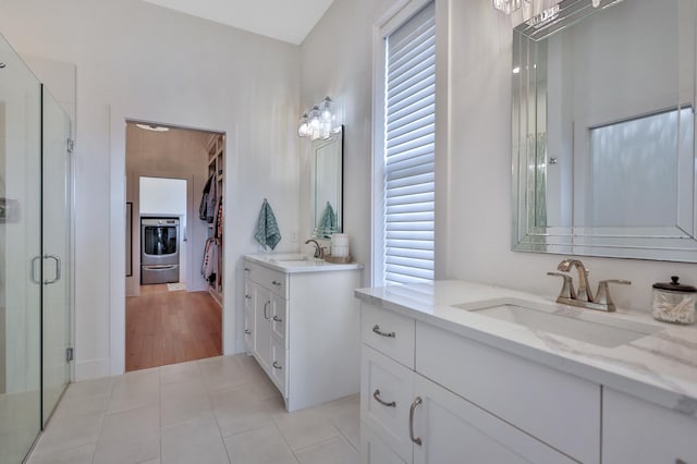 bathroom featuring tile patterned flooring, washer / clothes dryer, a sink, and a shower stall