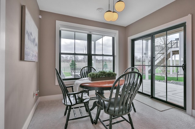 dining area with light carpet, a wealth of natural light, and baseboards