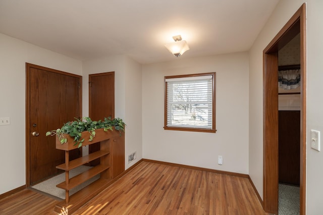 interior space featuring light wood-type flooring, visible vents, and baseboards