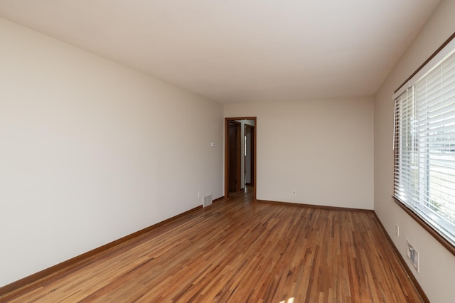 empty room featuring visible vents, light wood-style flooring, and baseboards