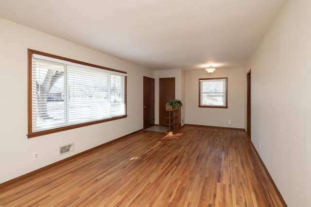 unfurnished room featuring light wood-style flooring, visible vents, and baseboards