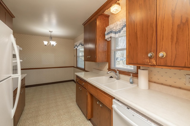 kitchen with baseboards, white appliances, a sink, and wallpapered walls