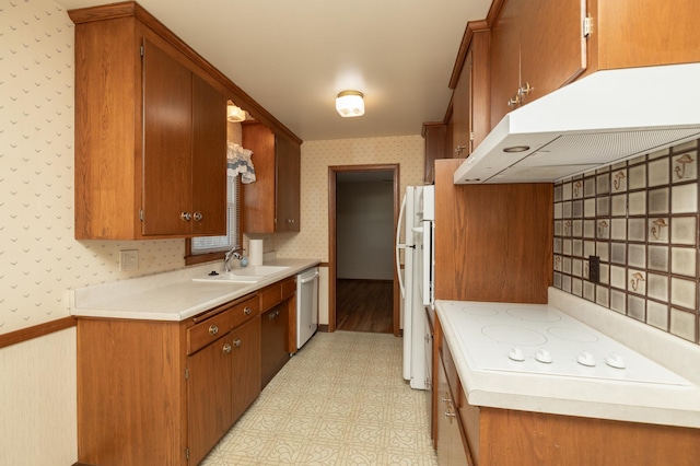 kitchen featuring under cabinet range hood, white appliances, a sink, light floors, and wallpapered walls