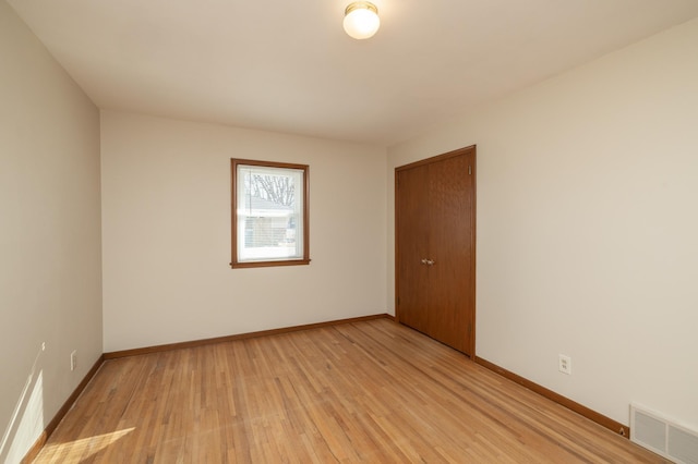 unfurnished room featuring light wood finished floors, visible vents, and baseboards