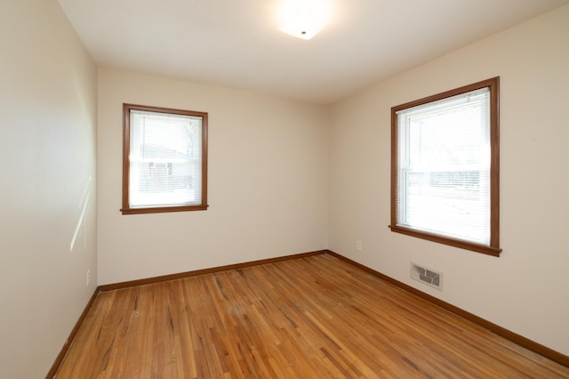 unfurnished room featuring light wood finished floors, baseboards, and visible vents