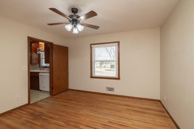 unfurnished room with baseboards, visible vents, a ceiling fan, light wood-type flooring, and a sink