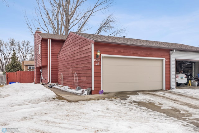 snow covered garage with fence