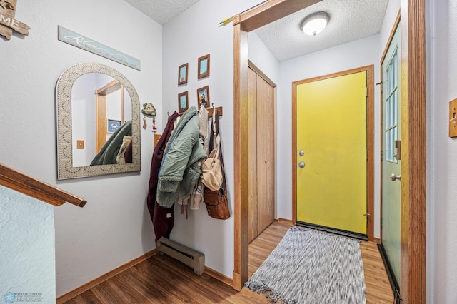 entryway featuring baseboards, a textured ceiling, baseboard heating, and wood finished floors