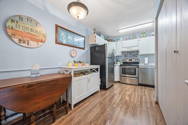 kitchen featuring stainless steel appliances, light wood-style flooring, white cabinetry, a textured ceiling, and under cabinet range hood