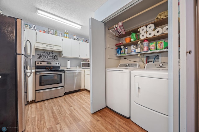 laundry area featuring a textured ceiling, laundry area, washer and clothes dryer, and light wood-style flooring