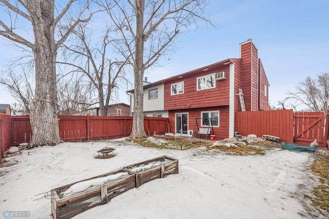 snow covered property featuring an outdoor fire pit, a chimney, and a fenced backyard