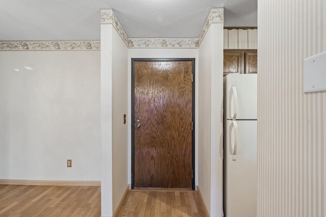 entryway with a textured ceiling, wood finished floors, and baseboards