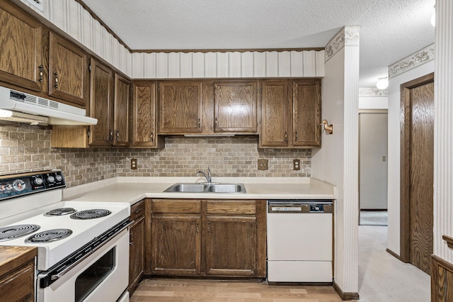 kitchen with white appliances, light countertops, a sink, and under cabinet range hood