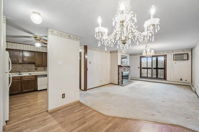 unfurnished living room featuring light wood-style flooring, a wall mounted air conditioner, baseboard heating, a textured ceiling, and a brick fireplace