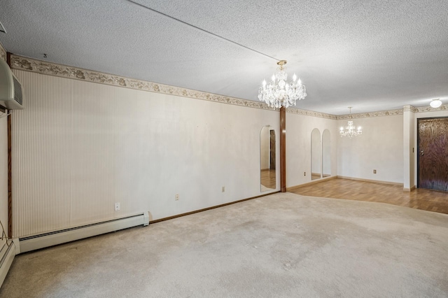 carpeted empty room featuring a chandelier, arched walkways, a baseboard heating unit, and a textured ceiling