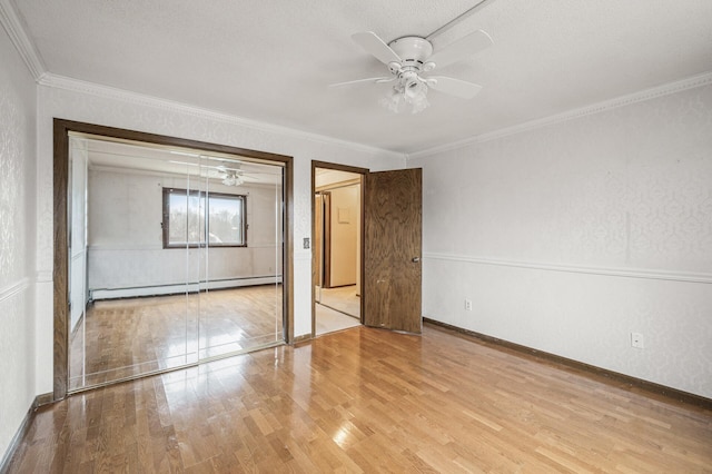 unfurnished bedroom with a baseboard radiator, ornamental molding, a ceiling fan, wood finished floors, and baseboards