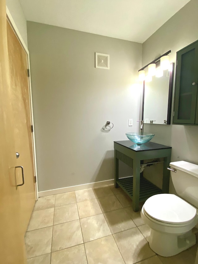 bathroom featuring visible vents, toilet, a sink, baseboards, and tile patterned floors