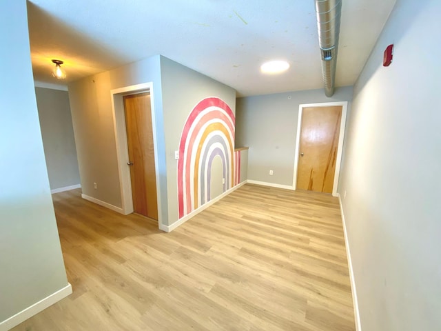 hall with light wood-style flooring and baseboards