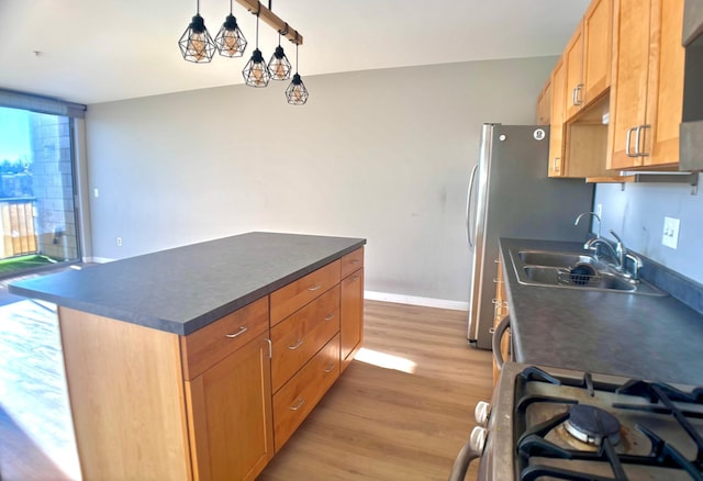 kitchen with dark countertops, light wood-style floors, a sink, a kitchen island, and baseboards