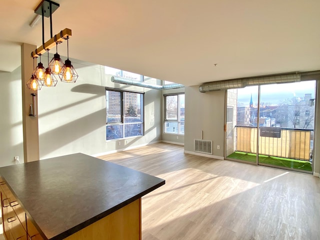 kitchen featuring visible vents, dark countertops, open floor plan, light wood-type flooring, and a notable chandelier