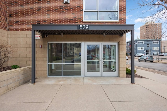 view of exterior entry with brick siding and french doors