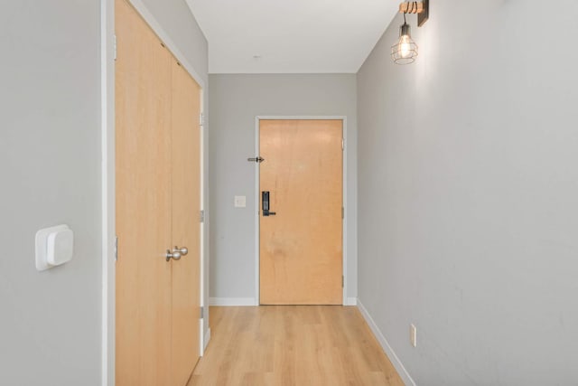 corridor with light wood finished floors and baseboards