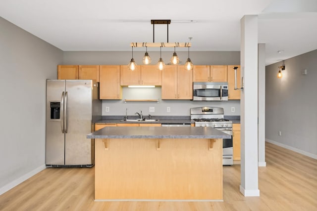 kitchen featuring a breakfast bar, light wood-style floors, appliances with stainless steel finishes, and a sink