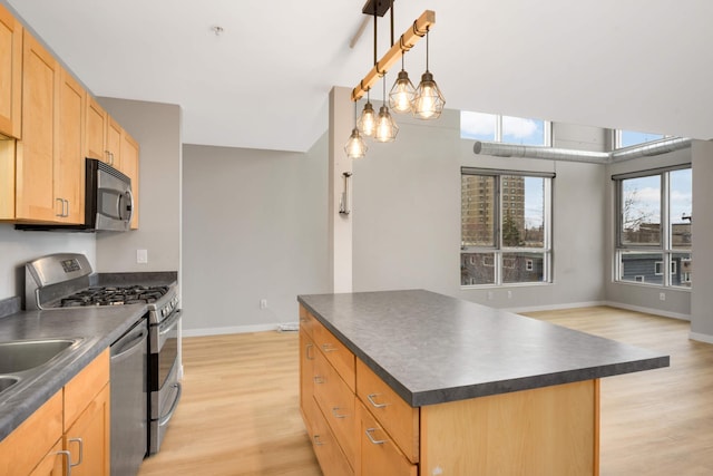 kitchen with stainless steel appliances, light wood-type flooring, dark countertops, baseboards, and a kitchen island