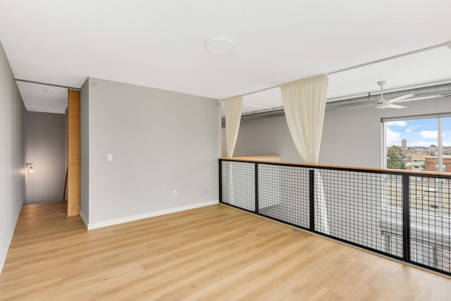 unfurnished room with wood finished floors, baseboards, and ceiling fan