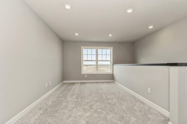 unfurnished room with recessed lighting, light colored carpet, and baseboards