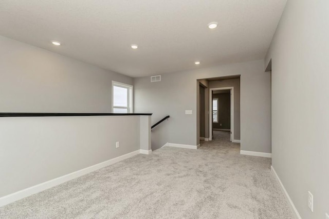 unfurnished room with recessed lighting, light colored carpet, and baseboards