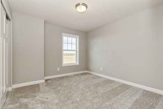 unfurnished room featuring light colored carpet and baseboards