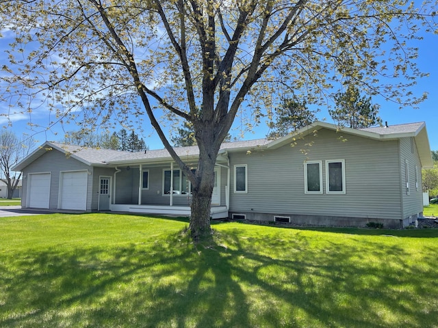 rear view of property with a garage, a yard, and driveway