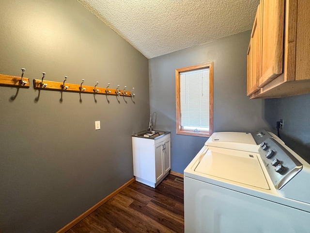 washroom featuring cabinet space, baseboards, dark wood-type flooring, washer and dryer, and a sink