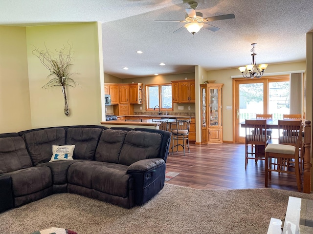 living area featuring recessed lighting, dark wood finished floors, a textured ceiling, and ceiling fan with notable chandelier