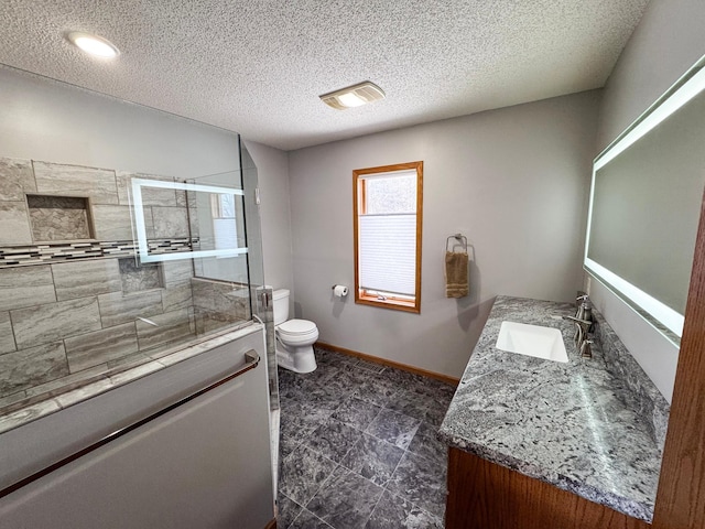 full bathroom with a textured ceiling, toilet, vanity, baseboards, and a tile shower