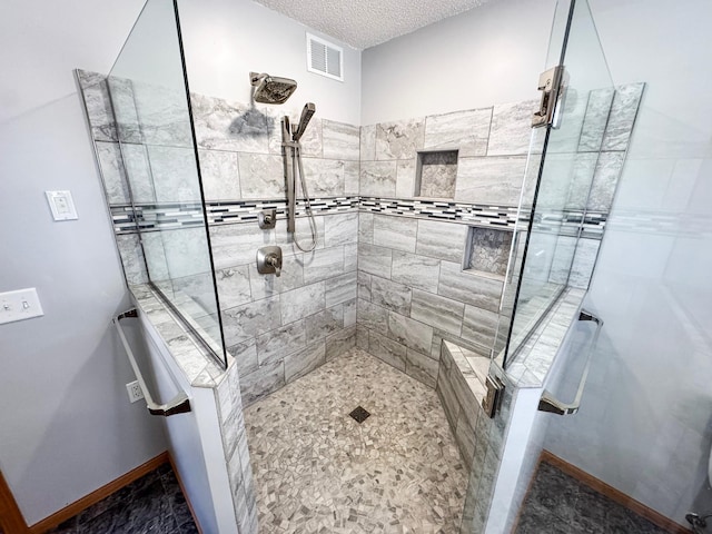 bathroom featuring baseboards, a textured ceiling, visible vents, and tiled shower