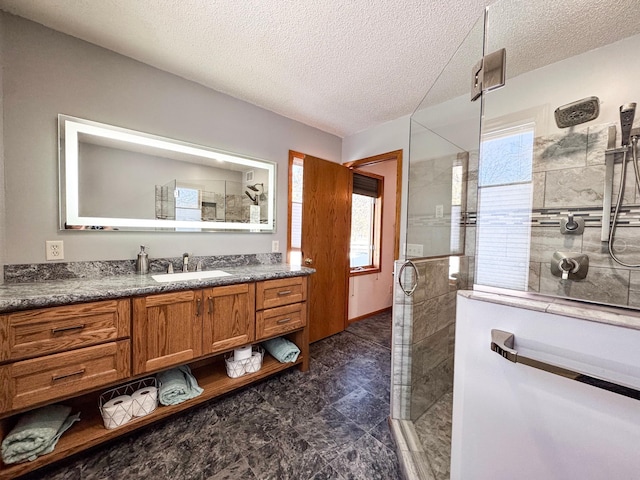 bathroom featuring a tile shower, a textured ceiling, and vanity