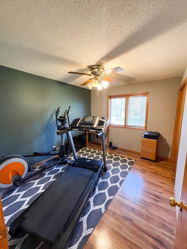 workout room featuring baseboards, a ceiling fan, and wood finished floors