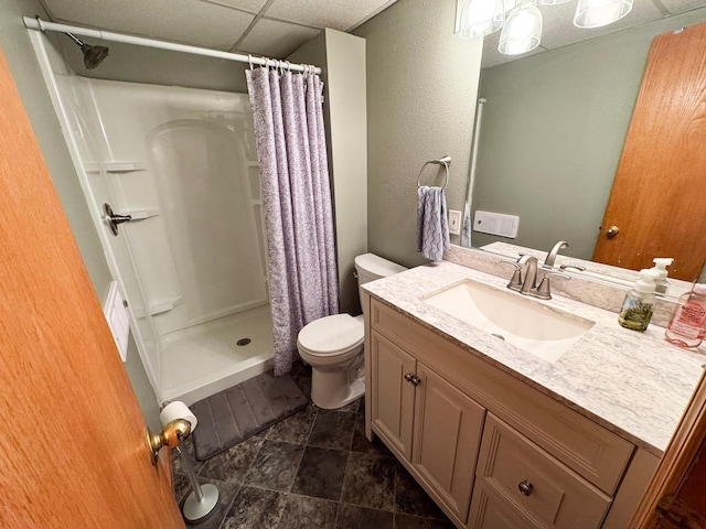 bathroom with a paneled ceiling, a shower stall, toilet, and vanity