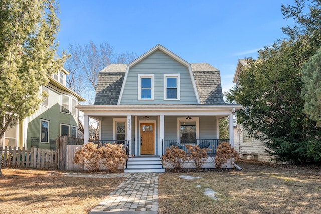 dutch colonial with a porch, roof with shingles, fence, and a gambrel roof