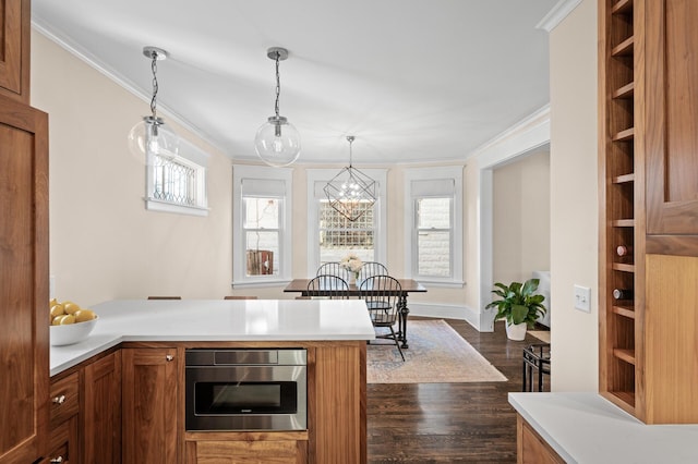 kitchen with dark wood-style floors, light countertops, brown cabinets, and crown molding